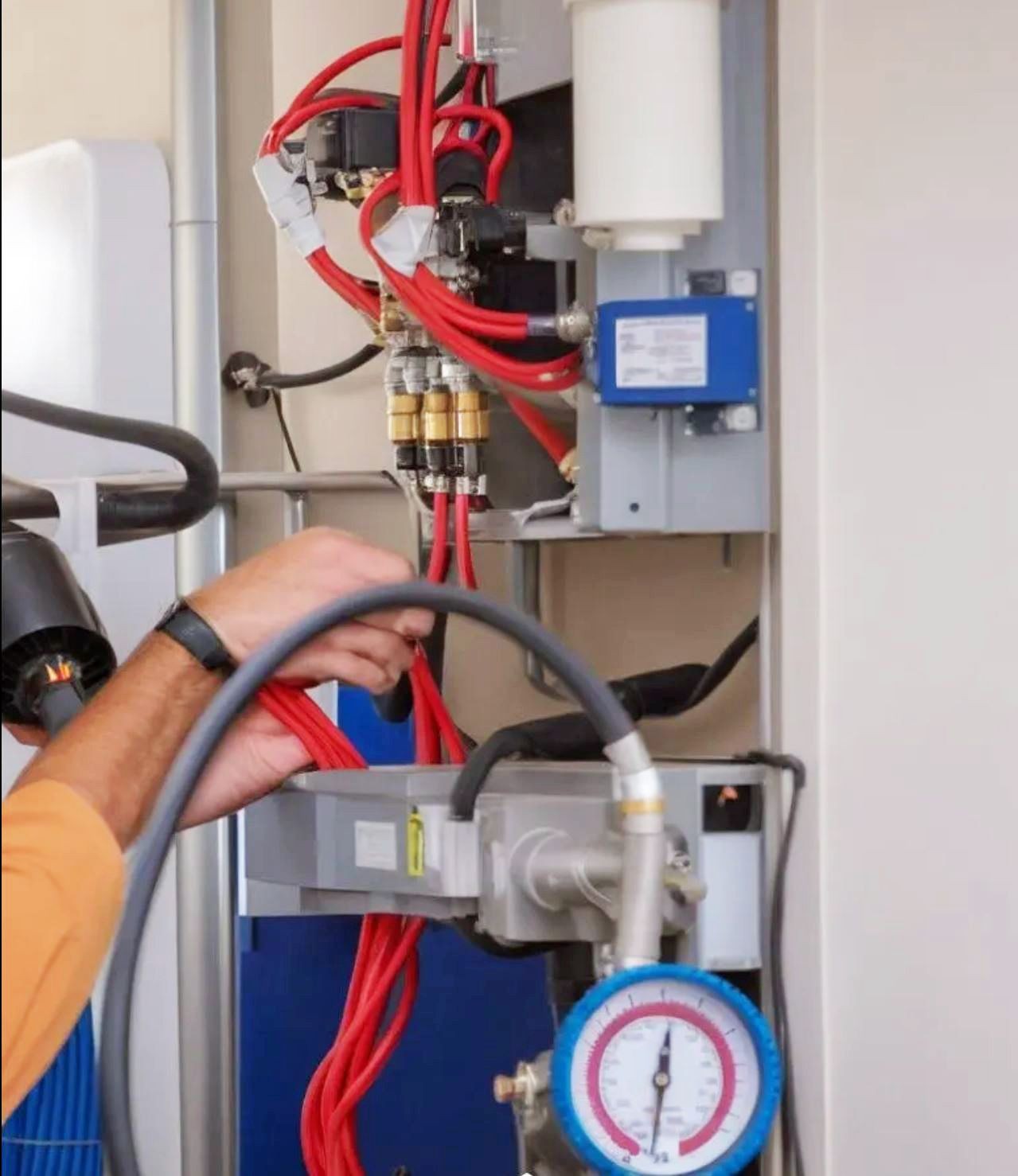 Person adjusting red cables and gauges in a technical equipment setup.